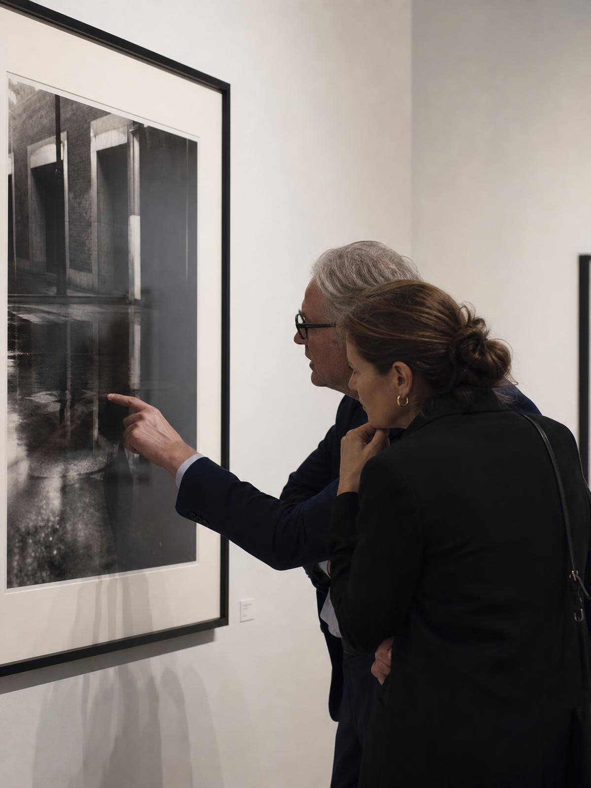 Collectors examining large-format photographic prints in a gallery
